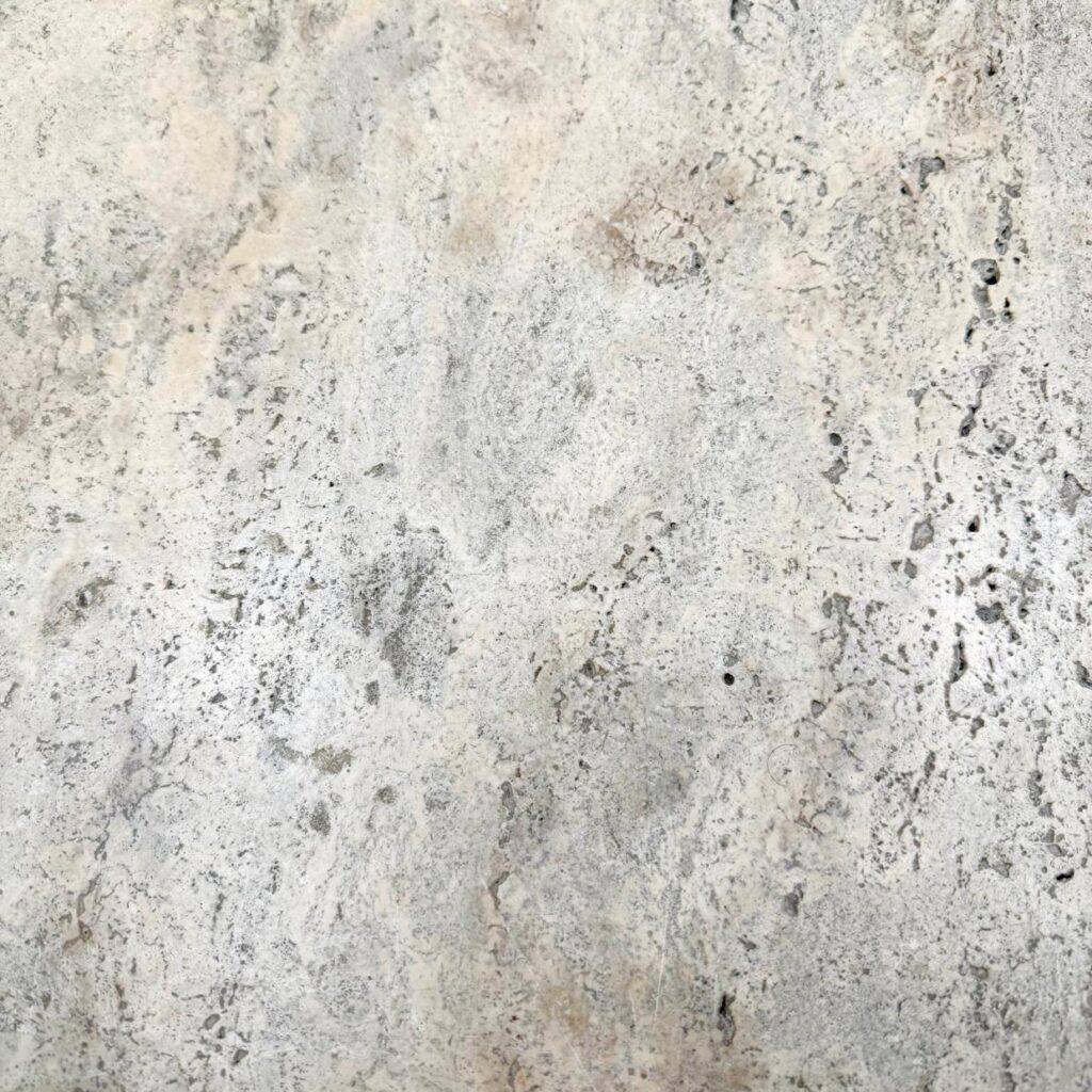 Close-up of Cashmere Travertine with creamy beige tones and natural swirls and pits.