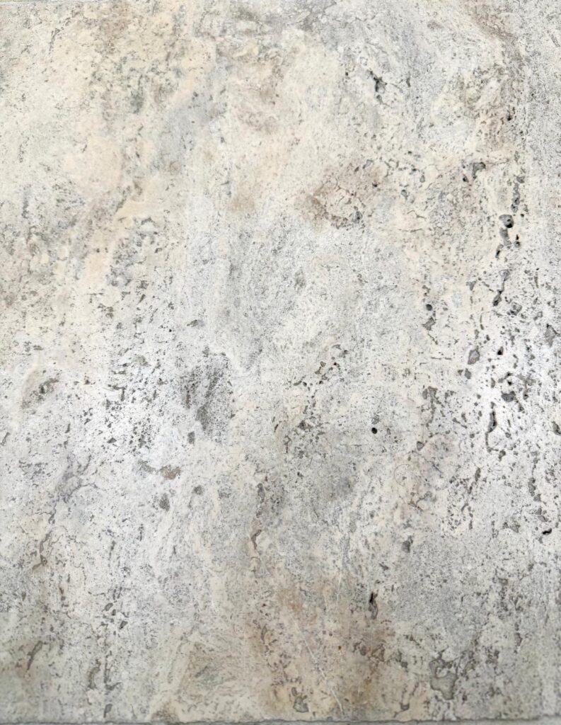 Close-up of Cashmere Travertine with creamy beige tones and natural swirls and pits.