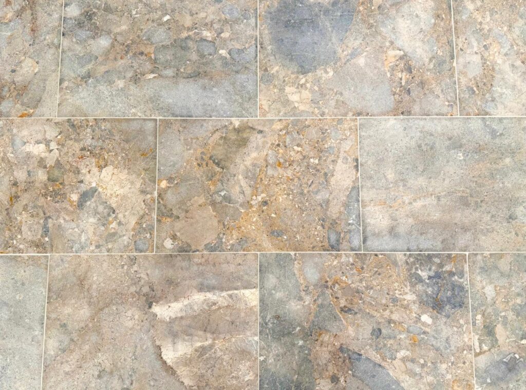 Atmos Marble tiles with earthy browns, greys, and golden fragments, featuring a richly textured and naturally variegated surface.