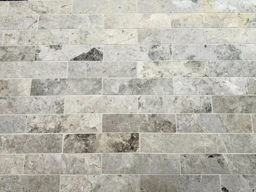 Ocean Grey Marble tiles arranged in a brick pattern, featuring soft grey tones with subtle veining and natural stone variations.