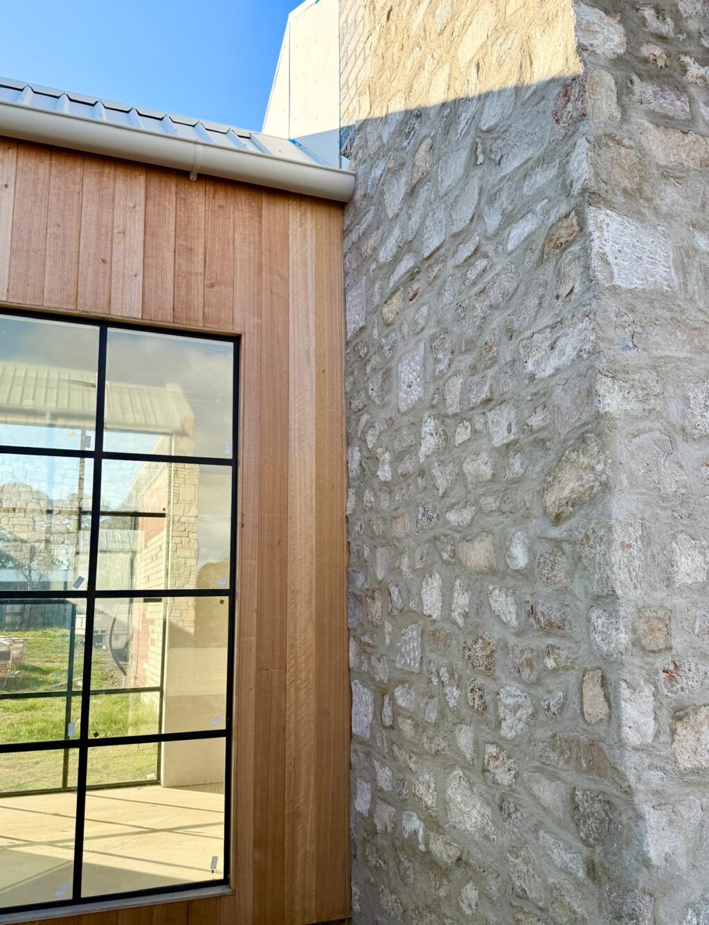 Sorrento Travertine wall next to vertical timber cladding and steel-framed window.