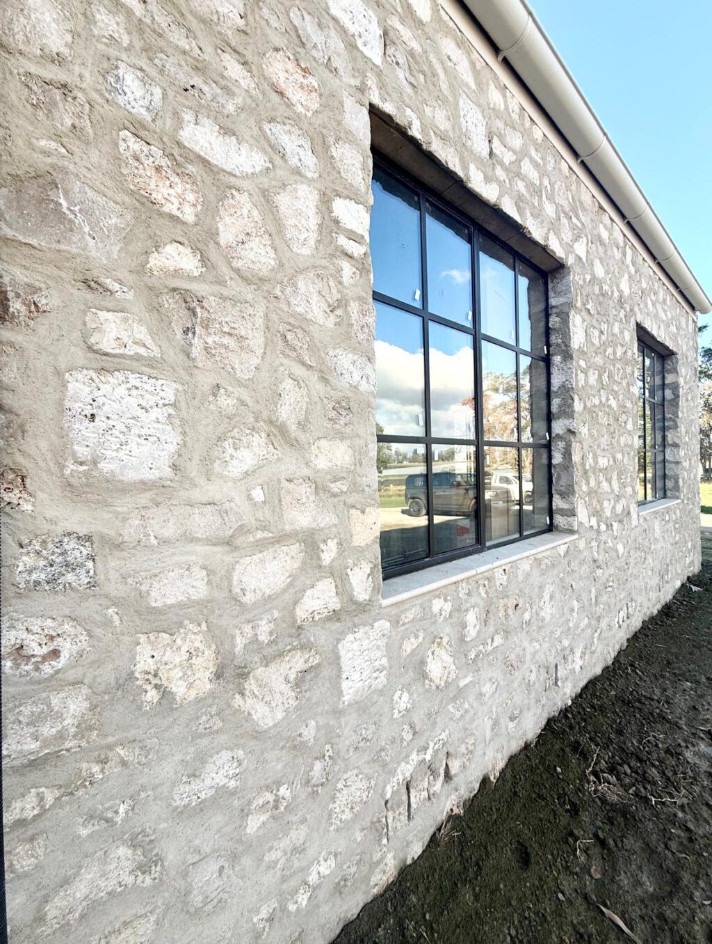 Sorrento Travertine wall with black steel-framed windows on a modern exterior.