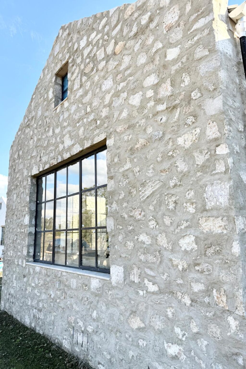 Facade clad in Sorrento Travertine with large black steel-framed window.
