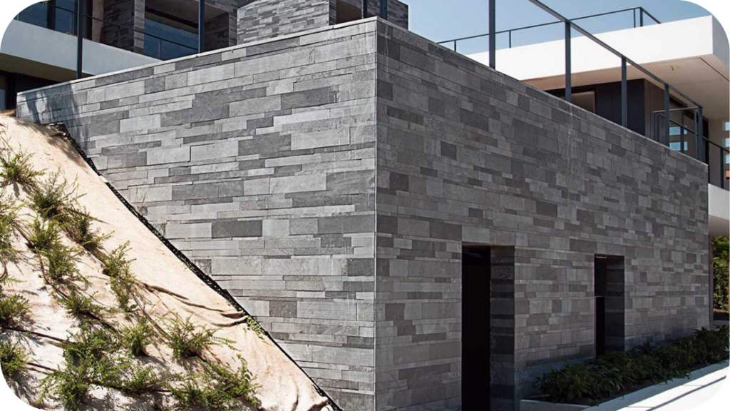 Bold grey stone cladding wraps the exterior of a modern Melbourne home with clean angles and flat rooflines.