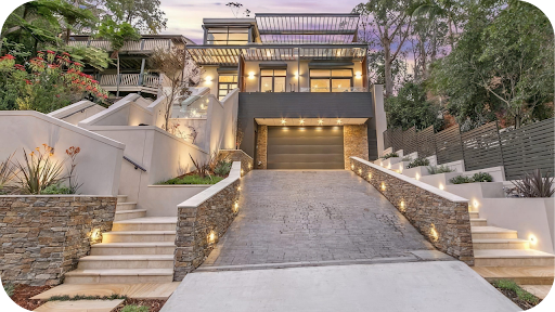 Modern Melbourne home with stone cladding lining the garage and stairways, surrounded by tiered garden lighting.