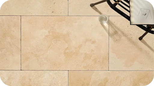 Ivory travertine pavers styled with a chair and glass of water, showcasing warm tones ideal for Melbourne interiors and outdoor designs.
