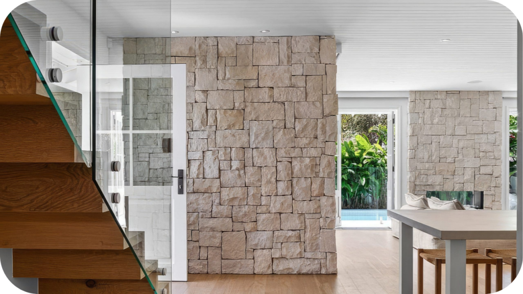 Light-toned stone cladding interior walls brightening a modern home with open spaces, timber floors, and glass doors to the garden.
