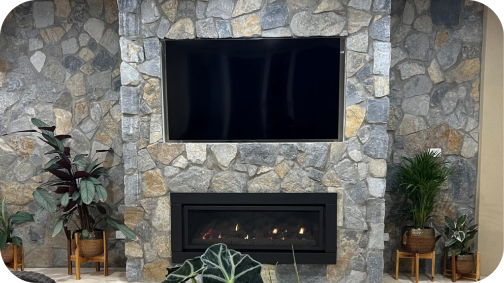 Natural stone cladding feature wall with built-in fireplace and mounted TV, styled with lush indoor plants for a modern look.