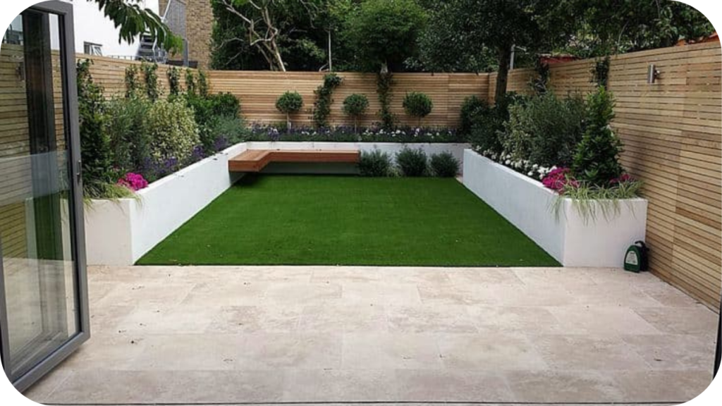 Modern backyard with stone patio, artificial lawn, raised garden beds, timber fencing, and a built-in wooden bench for outdoor living.
