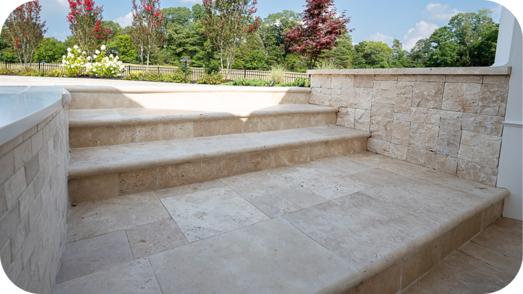 Stone steps leading to a landscaped garden with blooming trees and greenery, featuring natural beige tiles for a timeless outdoor look.