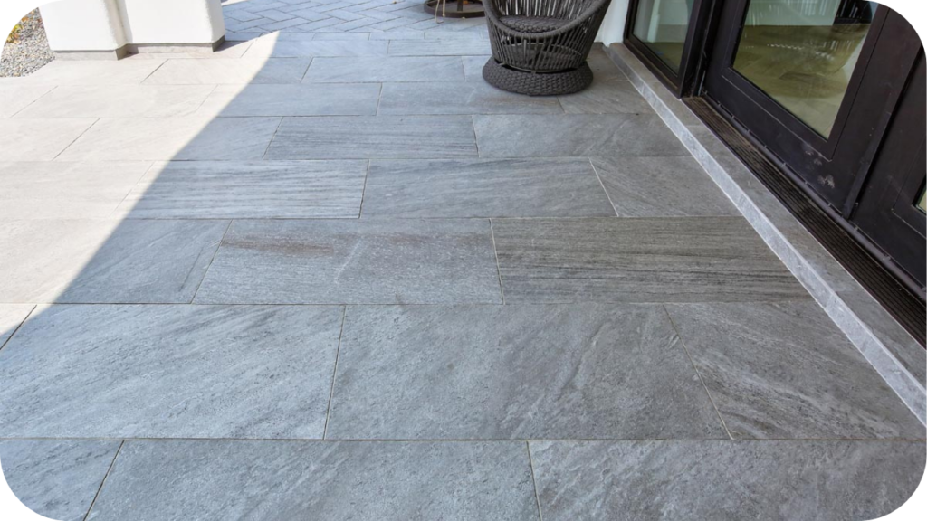 Light grey quartzite pavers installed on a modern outdoor patio beside glass doors, showing smooth texture and clean rectangular layout.