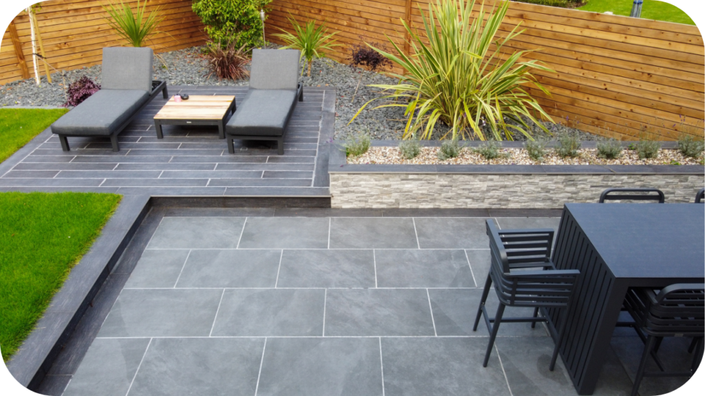 Modern backyard with grey natural stone pavers, lounge chairs, and a dining area showcasing sleek outdoor design for Melbourne living