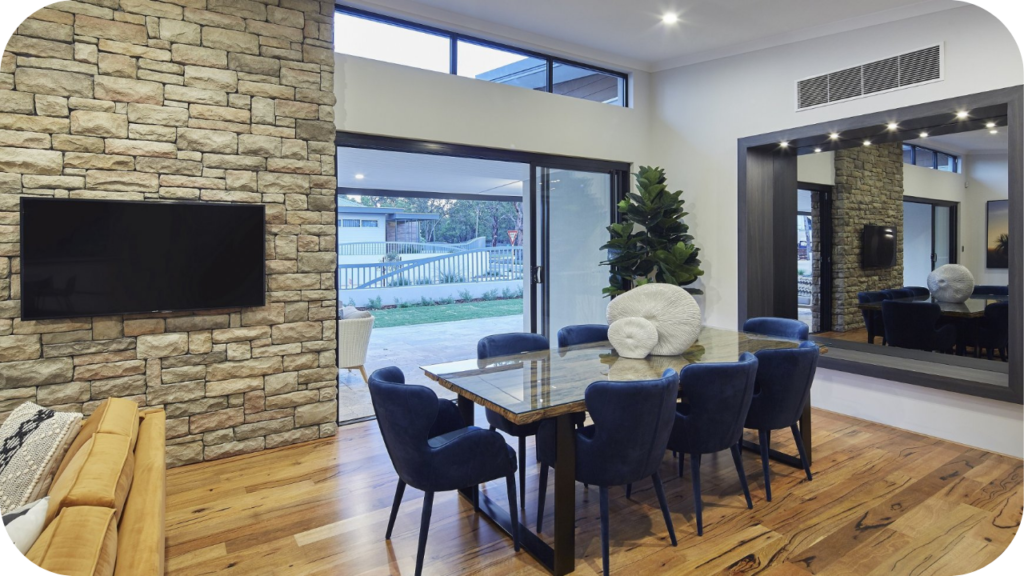 Dining room highlighted by natural stone cladding wall, large mirror, and timber floors, blending elegance with comfort.