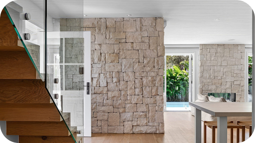 Modern Melbourne home with warm-toned stone cladding wall enhancing the staircase and open-plan living area.
