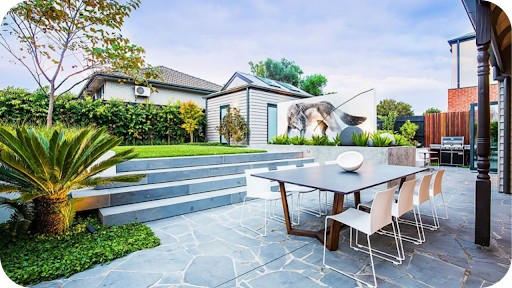 Outdoor entertaining area in the Northern Territory featuring crazy stone paving, garden steps, modern dining setup, and lush greenery.