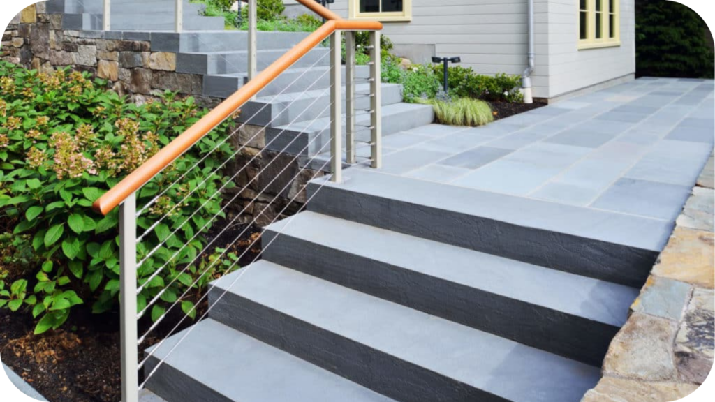 Contemporary outdoor steps in smooth bluestone with steel handrail, blending durability with modern landscape design.

