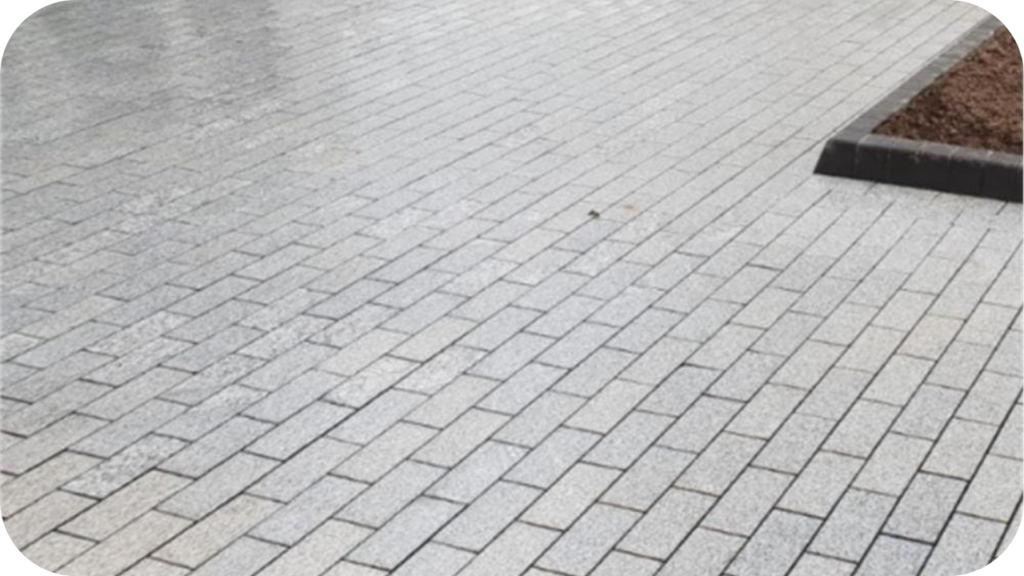 Worker installing granite pavers on a compacted gravel base, carefully aligning each block for an even surface.