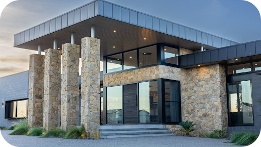 Contemporary residence featuring tall granite-clad pillars and large glass windows, combining natural stone with sleek architectural lines.