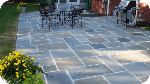 Bluestone-paved backyard with outdoor dining, a barbecue area, and garden plants showing how bluestone enhances functional outdoor spaces in Australian homes.