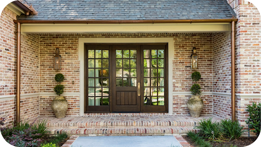 Classic brick home exterior with a timber front door, potted plants, and soft landscaping, showing how brick colour and texture shape an inviting façade.