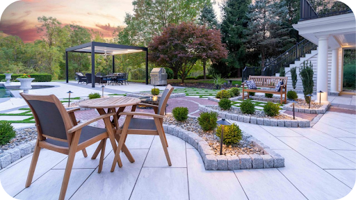 Outdoor patio with permeable stone paving, garden seating and landscaped pathways designed to support natural drainage in a modern backyard setting.