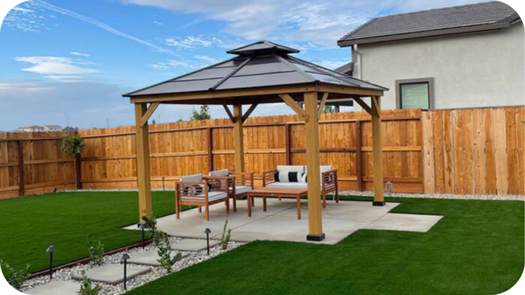 Garden gazebo on a paved platform surrounded by trimmed lawn and timber fencing, illustrating DIY ideas for choosing materials and creating outdoor seating zones.