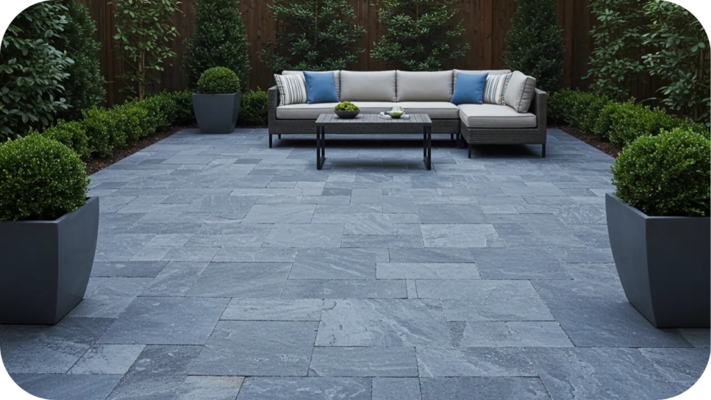 Blue-toned bluestone courtyard featuring a modern outdoor sofa, potted plants, and garden screening, creating a calm and elegant outdoor living space.