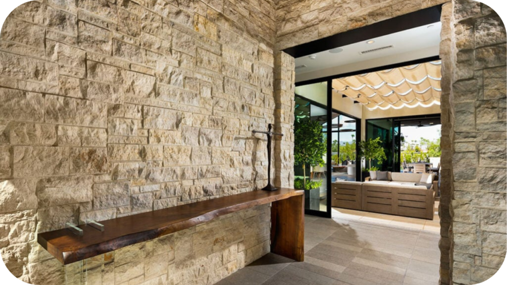 Light-textured natural stone wall in a modern entryway leading to an outdoor entertaining space, creating a refined transition between indoor and outdoor areas.