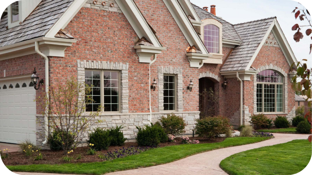 Brick façade paired with natural stone accents and neatly kept gardens, demonstrating how brick and stone work together to elevate exterior design.