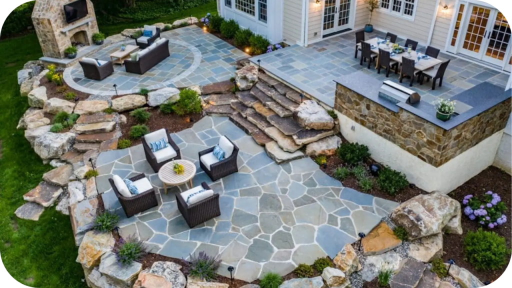 A multi-level outdoor entertaining area with natural stone paving, garden beds, and seating, showing how natural stone enhances Australian home landscaping.